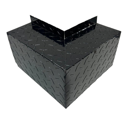 A black metal corner guard with a diamond plate texture, designed to provide protection to wall corners from damage. The shiny surface reflects light, highlighting the intricate pattern. With simple and easy installation, this Residential Series - Line Set Cover Outside Corner Elbows - Premium Quality by Perma Cover seamlessly fits into any space.