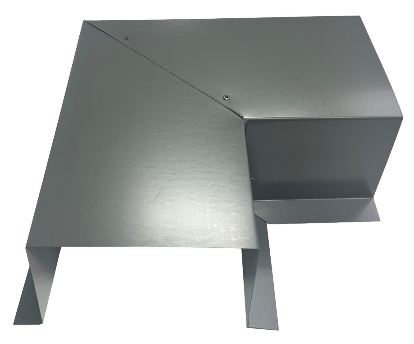 A metallic, angular object with a geometric design featuring sharp edges and flat surfaces. It has a reflective, smooth finish and appears to be part of a mechanical or industrial assembly. The object includes Perma Cover Residential Series - Line Set Cover Side Turning Elbows - Premium Quality, screws, and a folded structure for easy installation.