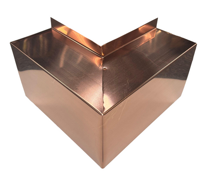 A shiny, copper-colored, angular metal object with multiple flat surfaces is shown. The object has a V-shaped structure with a vertical panel on top and reflective surfaces, appearing modern and industrial. This Perma Cover Residential Series - Line Set Cover Outside Corner Elbows - Premium Quality ensures simple and easy installation for any HVAC line set cover system.