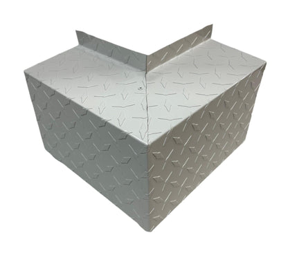 A metallic right-angle corner piece with a diamond plate pattern, commonly used for industrial or construction purposes. The Perma Cover Residential Series - Line Set Cover Outside Corner Elbows - Premium Quality boasts a reflective, textured surface and is designed to fit around the corner of a structure for protection or reinforcement with simple and easy installation.