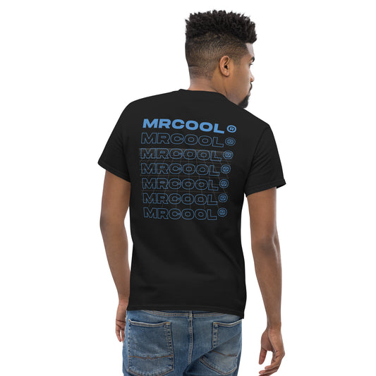 A young man viewed from behind, wearing a black "MRCOOL DIY Direct Signature Tee" printed repeatedly in blue and white. He has a short, stylish haircut and is wearing blue jeans.