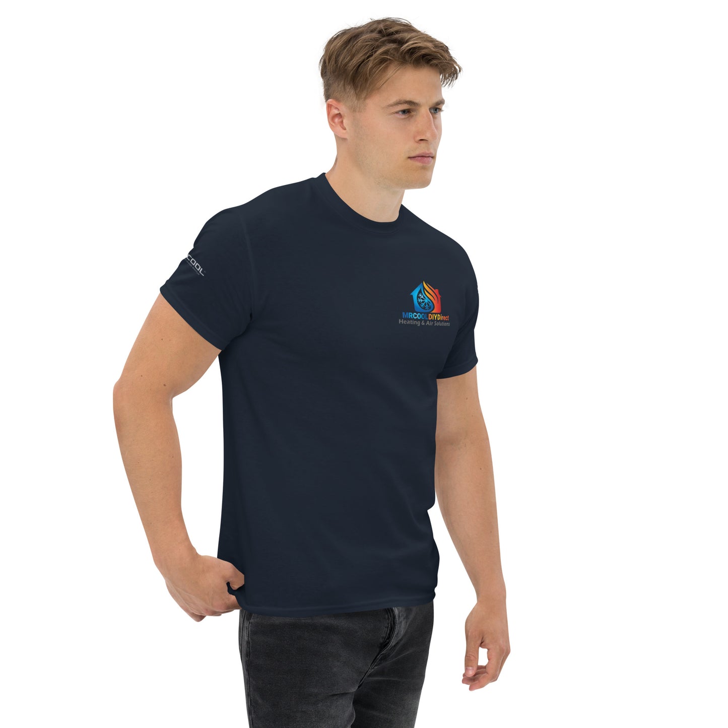 A young man wearing a dark blue Exclusive HVAC-Themed Custom Tee by MRCOOL DIY Direct, with a small logo on the left chest area, standing against a plain white background, looking slightly to the side.