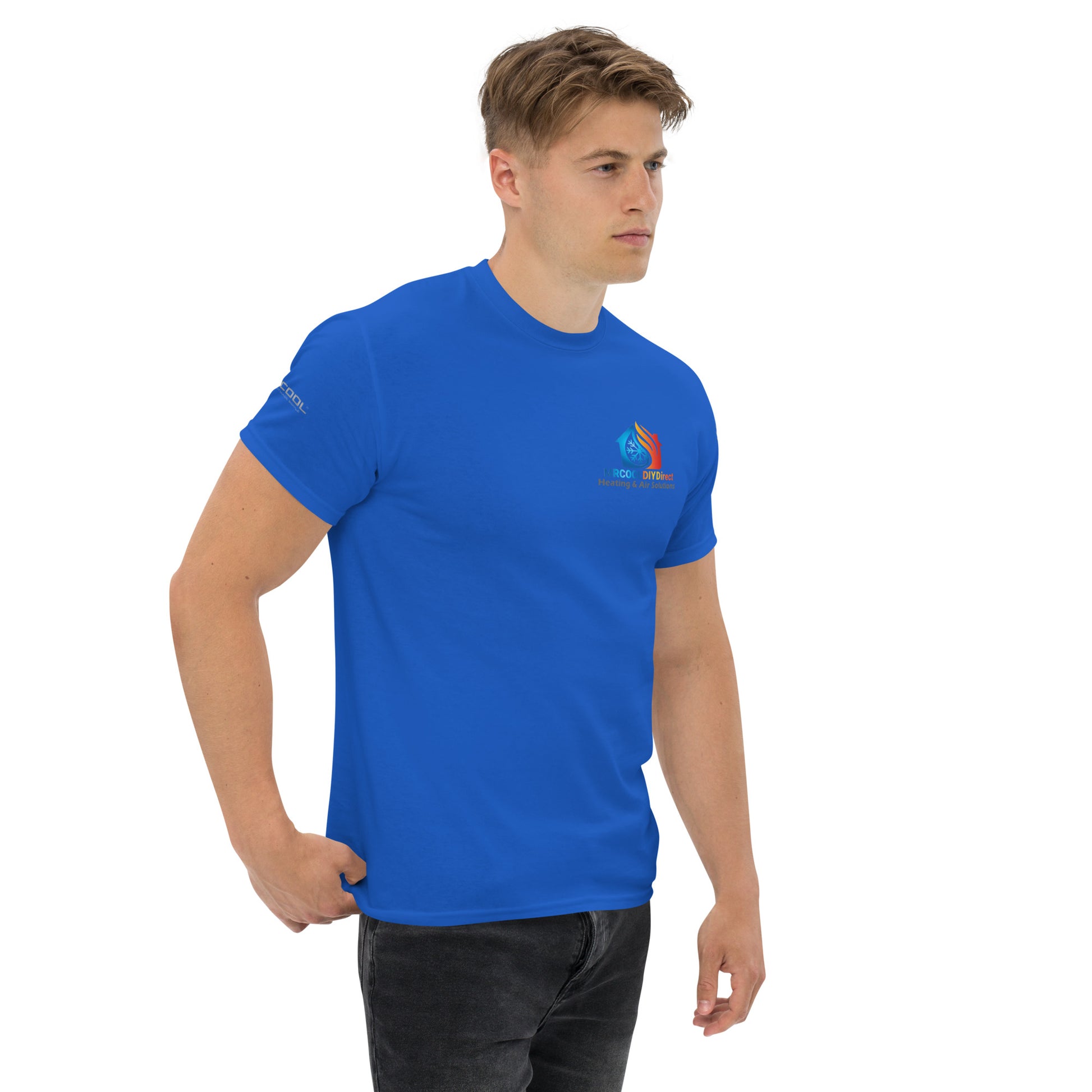 A young man wearing an Exclusive HVAC-Themed custom-designed royal blue t-shirt by MRCOOL DIY Direct with a colorful logo on the left chest stands against a white background, looking to his right.